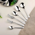 Stainless steel kitchen utensils set with spoons and forks on a beige background