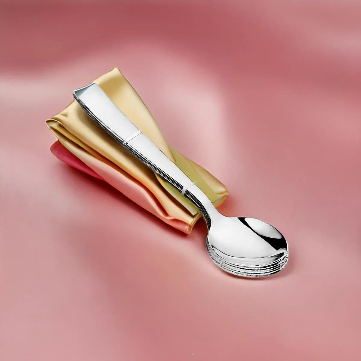 Stainless steel kitchen utensils, stacked spoons on pastel napkins on a pink background