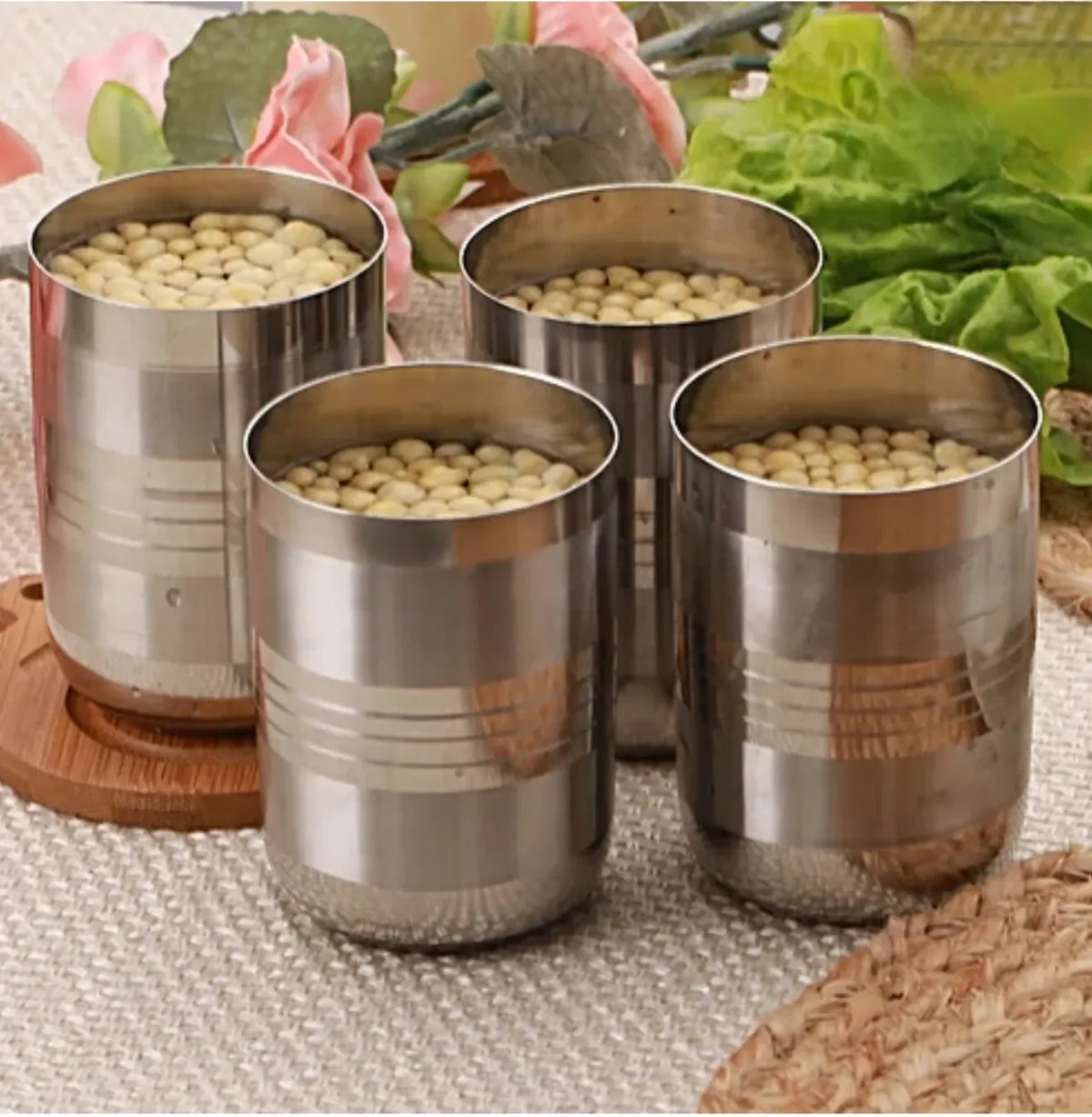 Set of four stainless steel kitchen utensil containers filled with soybeans